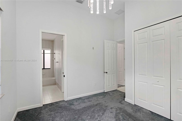 unfurnished bedroom featuring a closet, dark carpet, and ensuite bathroom