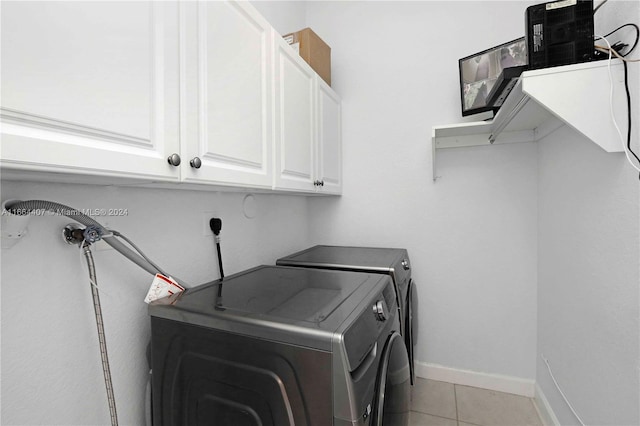 clothes washing area featuring cabinets, washing machine and clothes dryer, and light tile patterned floors