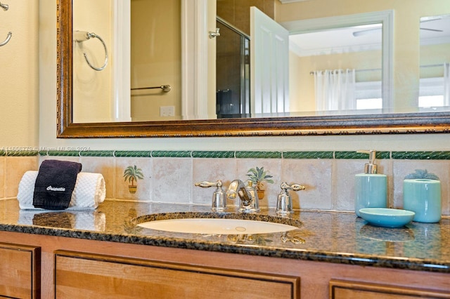 bathroom featuring tasteful backsplash, a shower with door, vanity, and crown molding