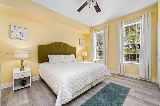 bedroom featuring ceiling fan, a textured ceiling, and light hardwood / wood-style flooring