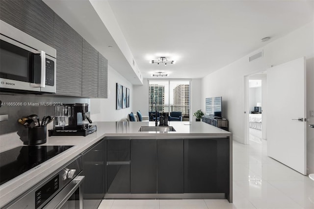 kitchen featuring sink, appliances with stainless steel finishes, kitchen peninsula, and light tile patterned flooring