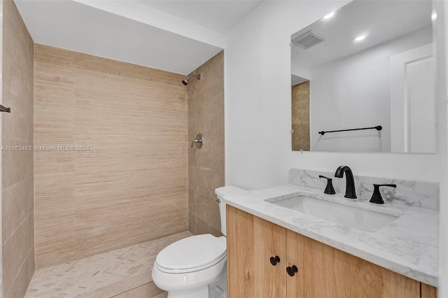 bathroom with tiled shower, vanity, toilet, and tile patterned floors