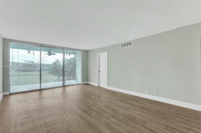 empty room featuring expansive windows and hardwood / wood-style floors