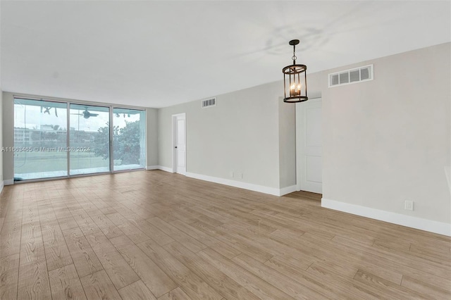 unfurnished room featuring light hardwood / wood-style floors, floor to ceiling windows, and a notable chandelier