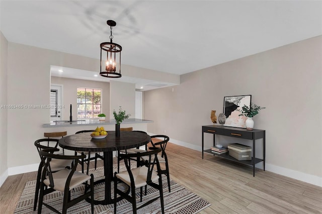 dining space featuring a notable chandelier, sink, and light hardwood / wood-style floors