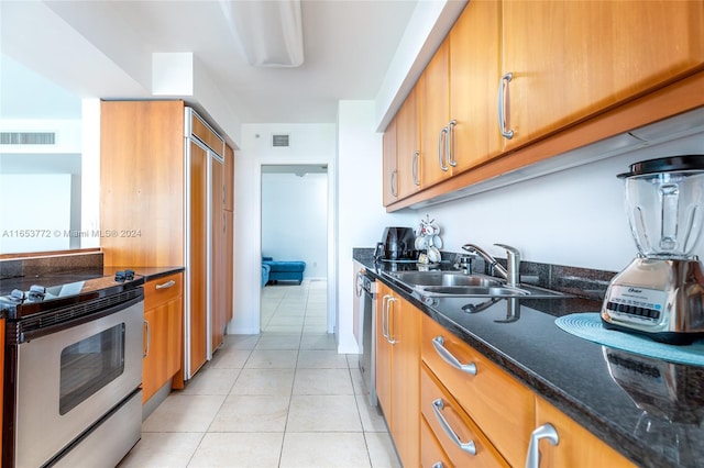 kitchen featuring sink, white range with electric stovetop, light tile patterned floors, dark stone countertops, and stainless steel dishwasher