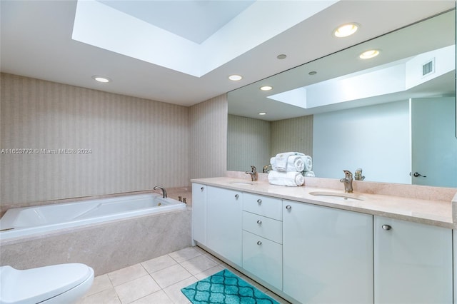 bathroom with tile patterned flooring, a skylight, tiled bath, vanity, and toilet