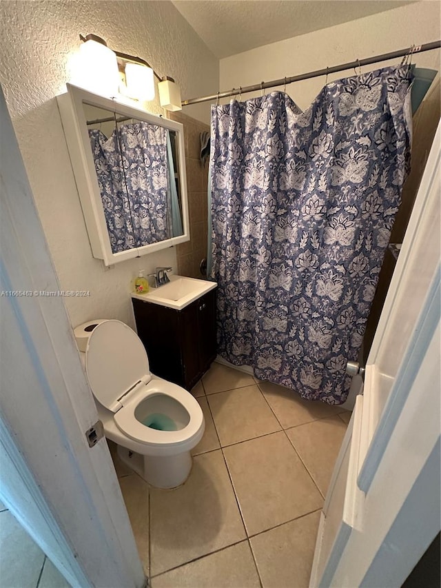 bathroom with a textured ceiling, toilet, vanity, a shower with shower curtain, and tile patterned flooring