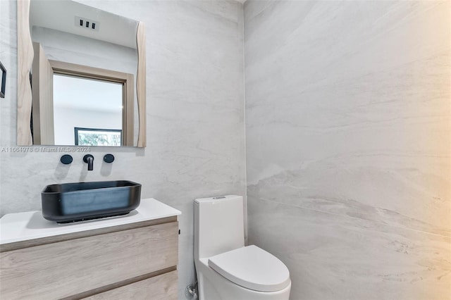 bathroom featuring vanity, tile walls, and toilet