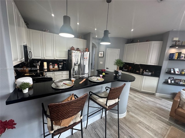 kitchen with light hardwood / wood-style floors, appliances with stainless steel finishes, white cabinetry, and decorative backsplash