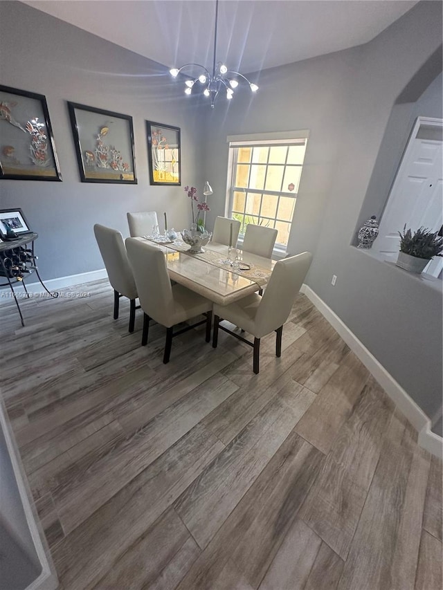 dining room with lofted ceiling, an inviting chandelier, and hardwood / wood-style flooring