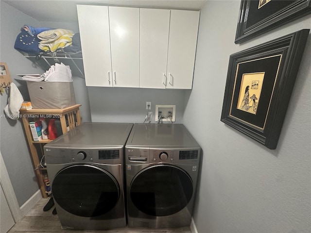 washroom with washer and dryer and cabinets