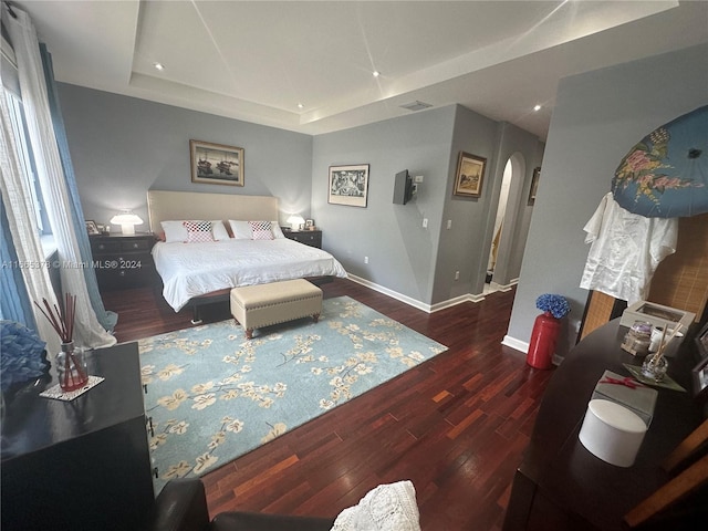 bedroom featuring a raised ceiling and dark hardwood / wood-style flooring