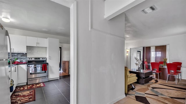 kitchen featuring white cabinets, stainless steel range, and tasteful backsplash