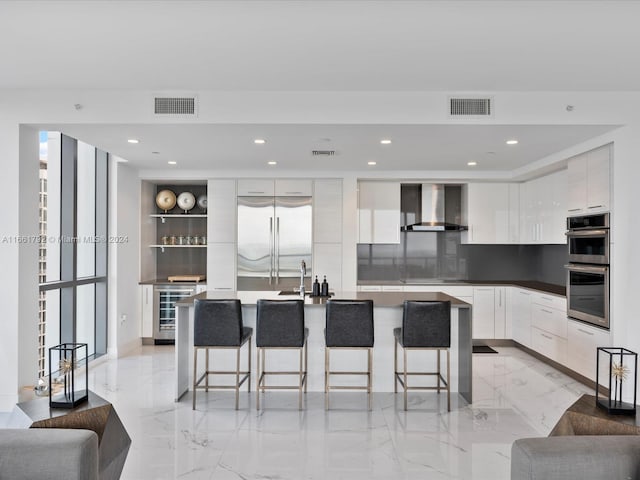 kitchen with a wealth of natural light, appliances with stainless steel finishes, wall chimney range hood, and white cabinetry