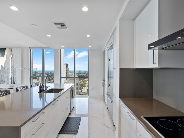 kitchen with black electric cooktop, sink, a spacious island, and white cabinets