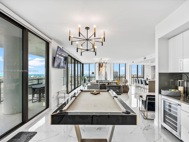 game room with pool table, a wall of windows, wine cooler, and a notable chandelier