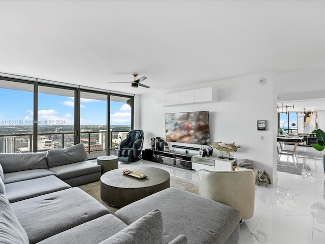 living room featuring ceiling fan with notable chandelier, floor to ceiling windows, and a wealth of natural light