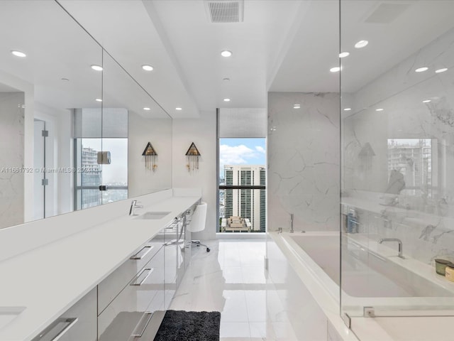 bathroom featuring a wealth of natural light, a tub, and vanity