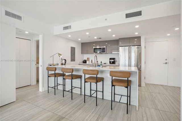 kitchen featuring gray cabinets, appliances with stainless steel finishes, sink, and a breakfast bar