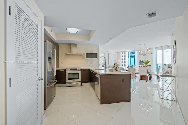 kitchen with wall chimney range hood, sink, stainless steel appliances, kitchen peninsula, and light tile patterned floors