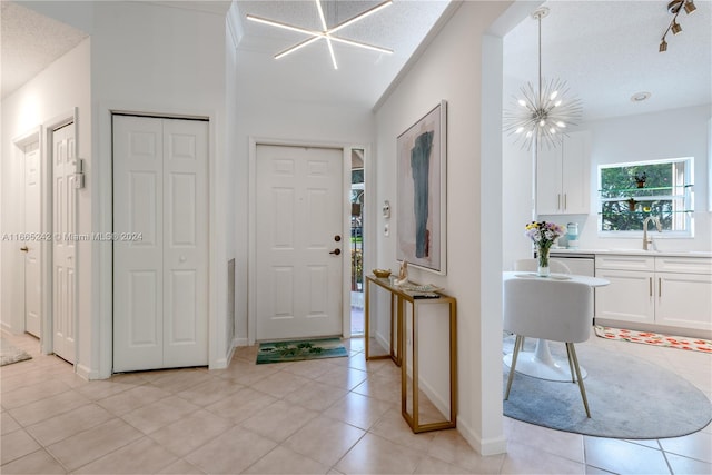 entryway featuring an inviting chandelier, a textured ceiling, light tile patterned flooring, and sink