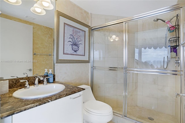 bathroom featuring vanity, toilet, and a shower with door