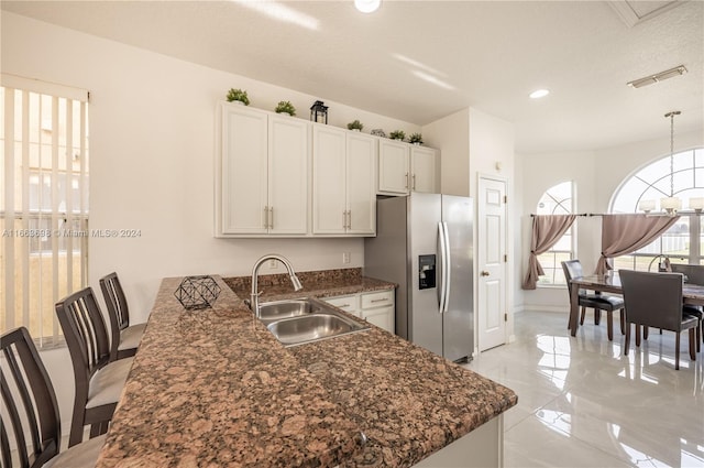 kitchen with kitchen peninsula, sink, pendant lighting, stainless steel fridge with ice dispenser, and white cabinetry