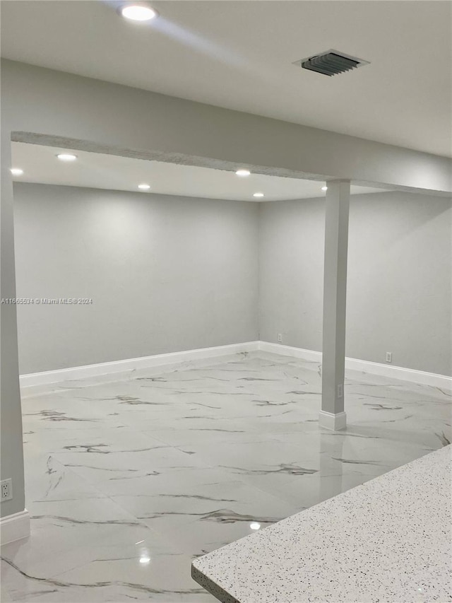 finished below grade area with baseboards, marble finish floor, and recessed lighting