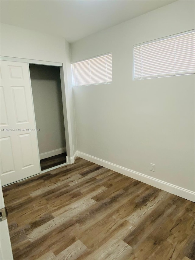 unfurnished bedroom with dark hardwood / wood-style floors and a closet