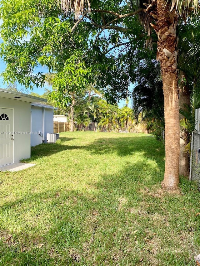 view of yard featuring fence, cooling unit, and an outdoor structure