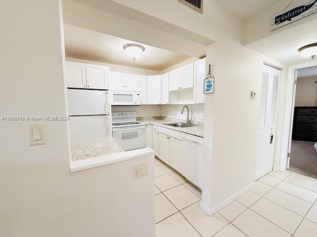 kitchen featuring white cabinets, sink, light tile patterned flooring, backsplash, and white appliances