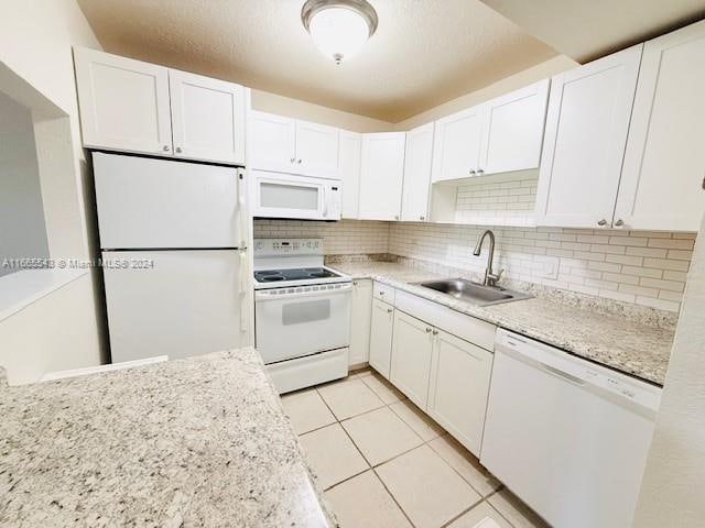 kitchen featuring light tile patterned flooring, sink, tasteful backsplash, white appliances, and white cabinets