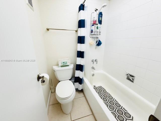 bathroom featuring toilet, tile patterned floors, and shower / tub combo