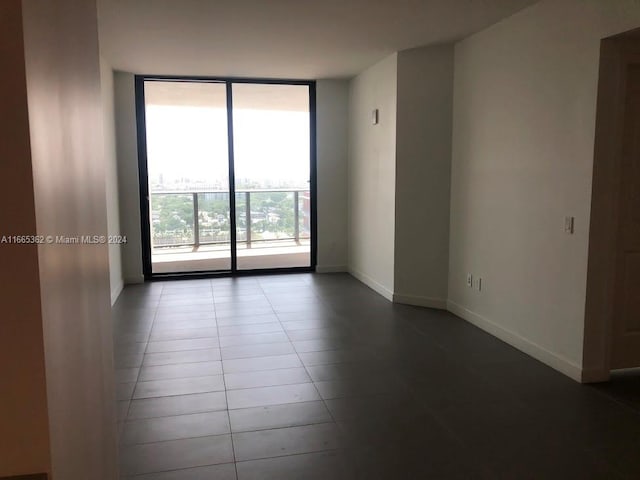 tiled empty room featuring floor to ceiling windows