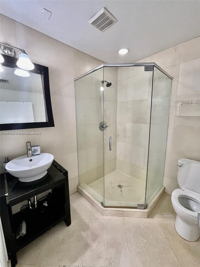 bathroom with tile walls, walk in shower, vanity, and toilet