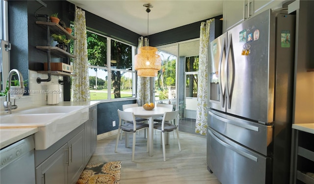 kitchen with pendant lighting, dishwasher, light hardwood / wood-style floors, stainless steel fridge with ice dispenser, and sink