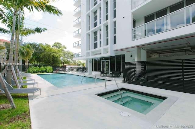 view of swimming pool featuring a community hot tub and a patio area