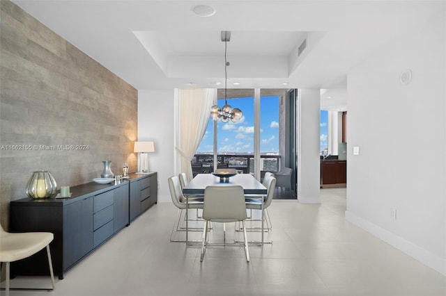 dining room with a raised ceiling, an inviting chandelier, and expansive windows