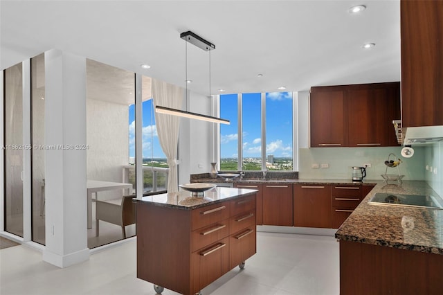 kitchen with dark stone countertops, pendant lighting, black electric stovetop, and a center island