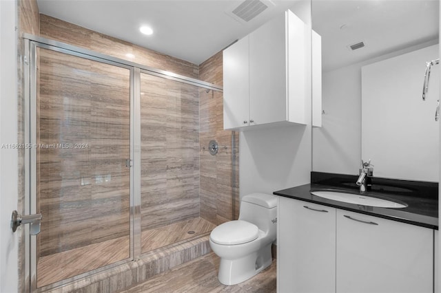 bathroom with hardwood / wood-style floors, walk in shower, vanity, and toilet