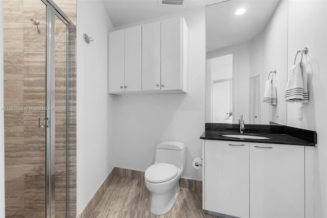 bathroom featuring wood-type flooring, vanity, toilet, and an enclosed shower