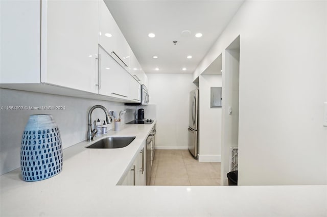 kitchen with white cabinets, electric panel, light tile patterned floors, sink, and stainless steel appliances