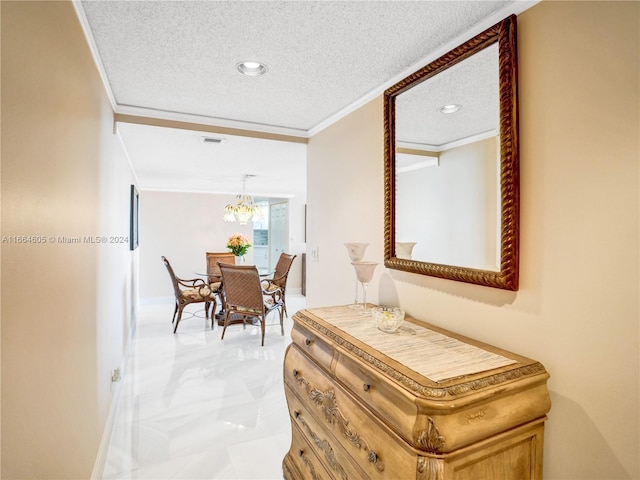 hallway featuring a textured ceiling, crown molding, and a notable chandelier