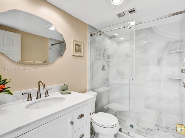 bathroom with a shower with door, vanity, and toilet