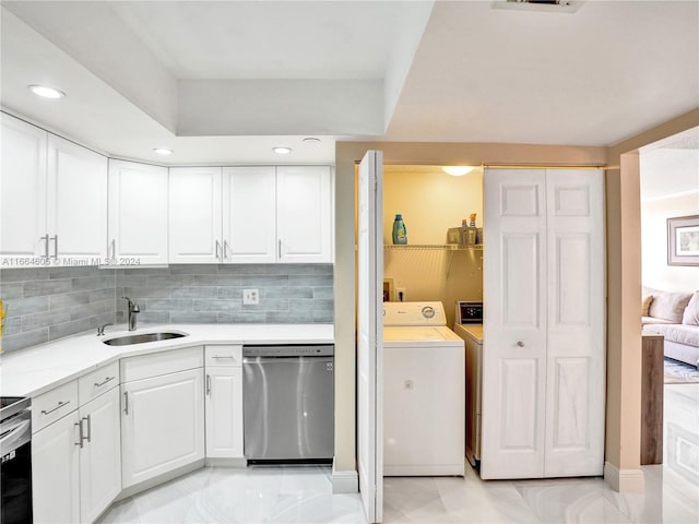 kitchen featuring independent washer and dryer, tasteful backsplash, white cabinets, stainless steel dishwasher, and sink