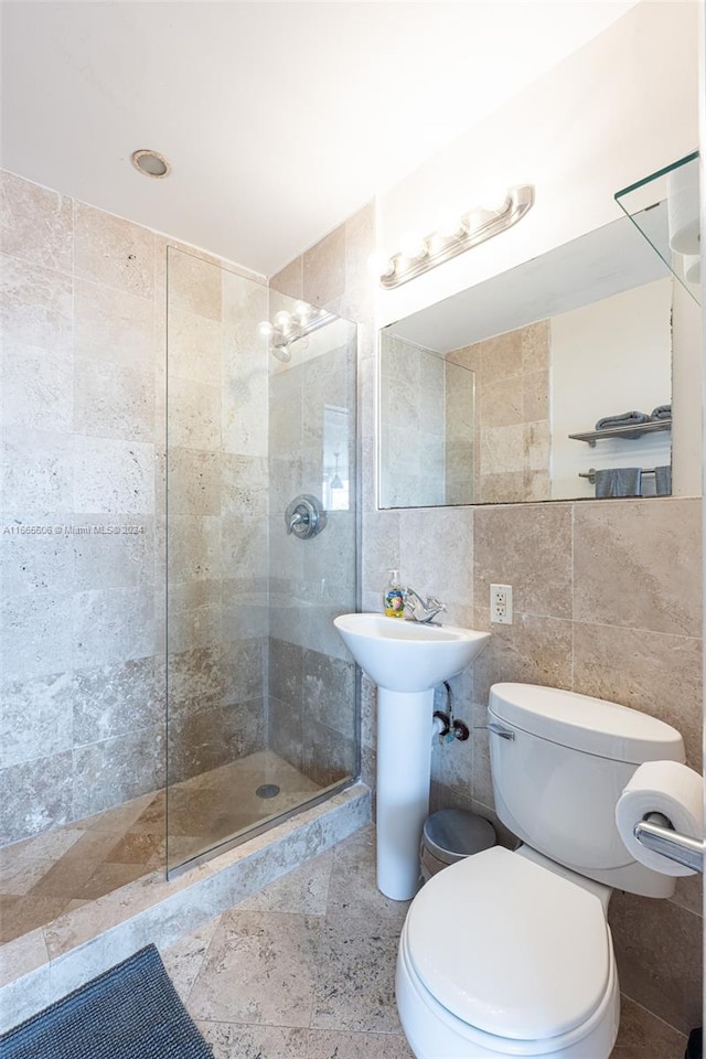 bathroom featuring a tile shower, tile walls, and toilet