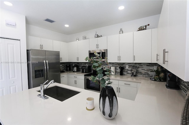 kitchen with stainless steel appliances, white cabinets, tasteful backsplash, and sink