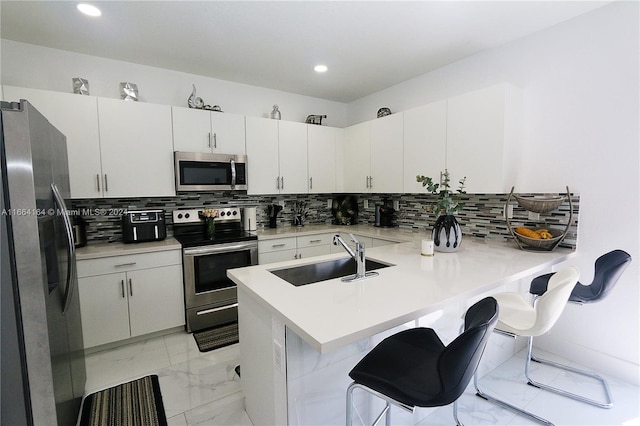 kitchen with kitchen peninsula, appliances with stainless steel finishes, sink, and a breakfast bar area