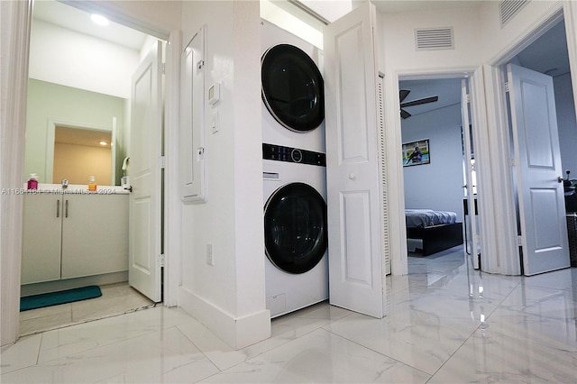 clothes washing area featuring ceiling fan and stacked washing maching and dryer